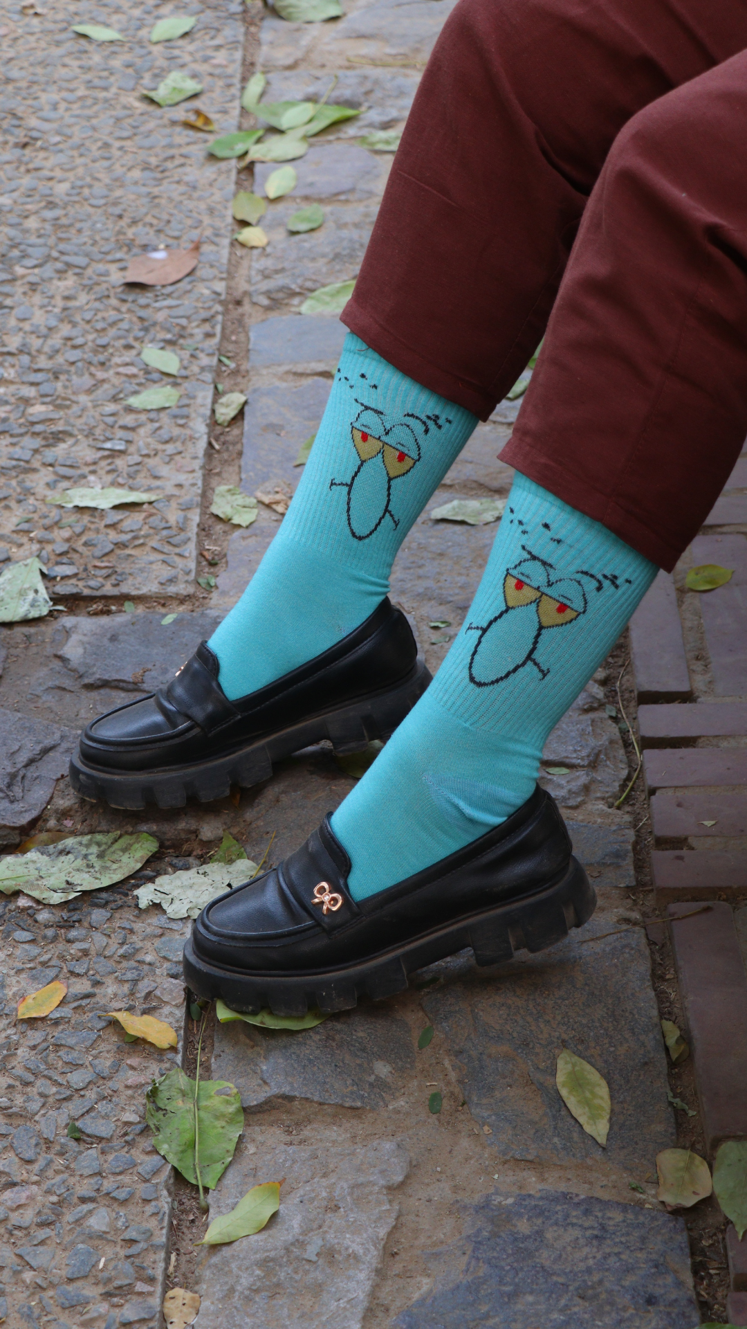 Model wearing Big Nose funky socks – cyan crew-length cotton socks with quirky cartoon nose emoji for a fun, bold look.