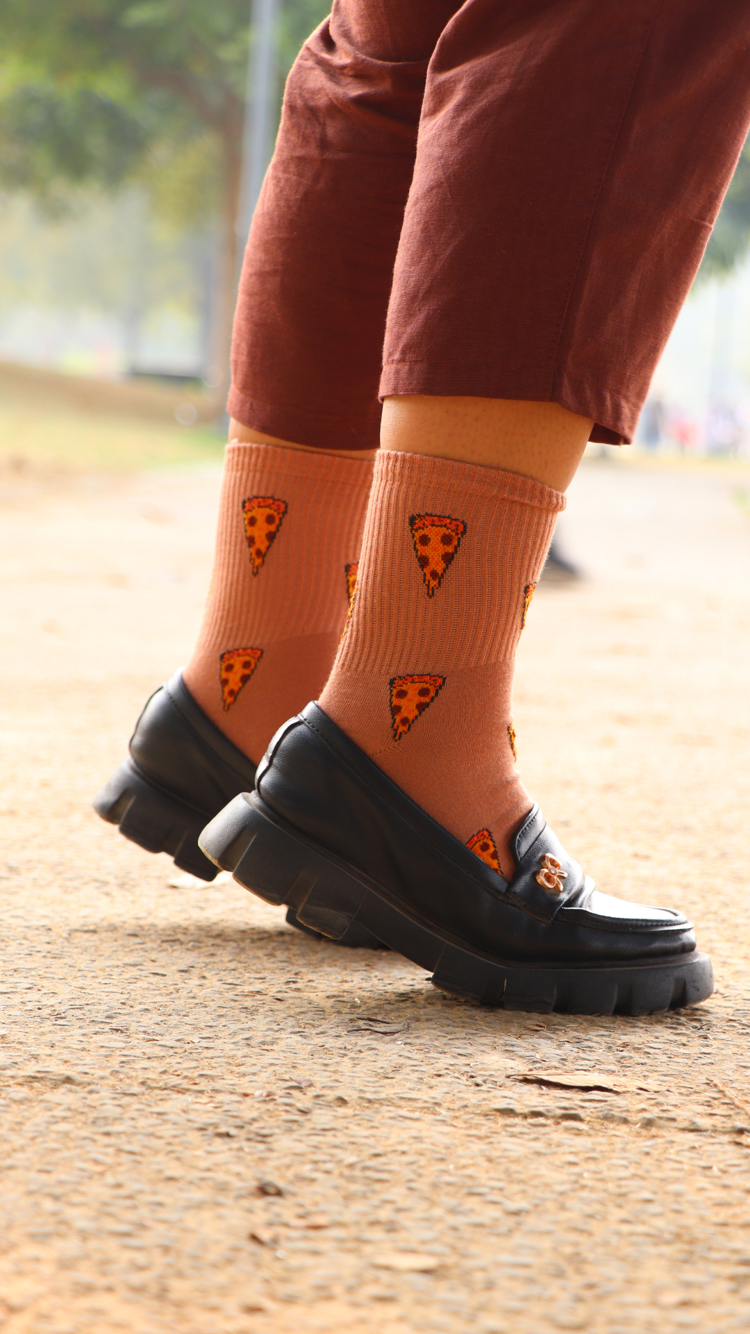 Model wearing Cheesy Pizza funky socks – brown ankel-length cotton socks with a playful pizza print, perfect for foodies and pizza lovers with a fun, casual style
