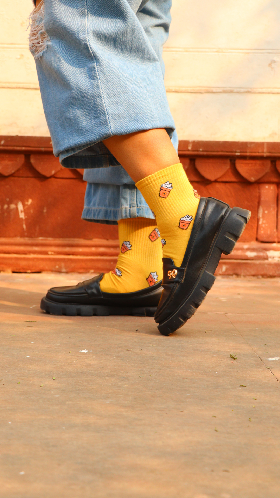 Model wearing Whipped Coffee funky socks – brown crew-length cotton socks with a delicious whipped coffee print, adding a cozy and caffeinated vibe to your outfit.