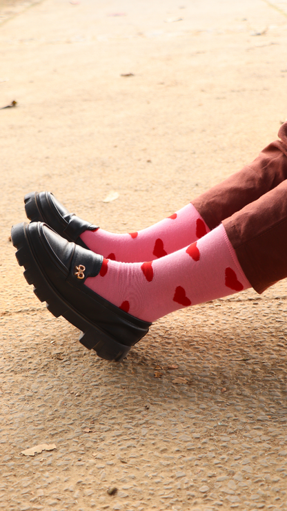Model wearing Take My Heart Pink funky socks – pink crew-length cotton socks with a vibrant heart print, perfect for adding a fun and loving touch to your everyday look.