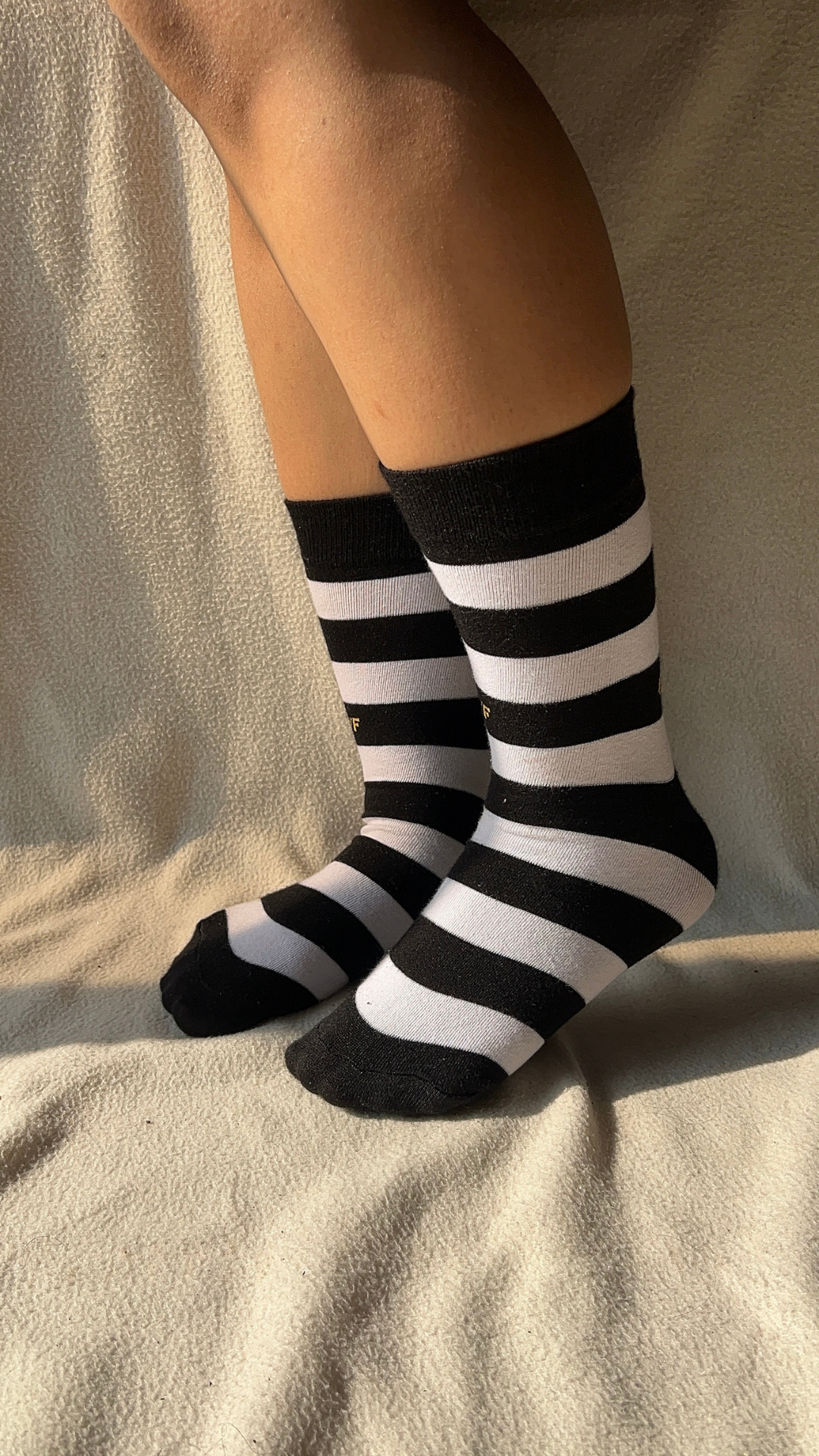 Model wearing Zebra Rush Crew funky socks – black crew-length cotton socks with bold zebra stripe pattern for a stylish and wild look.