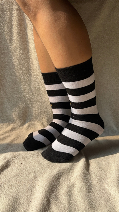 Model wearing Zebra Rush Crew funky socks – black crew-length cotton socks with bold zebra stripe pattern for a stylish and wild look.